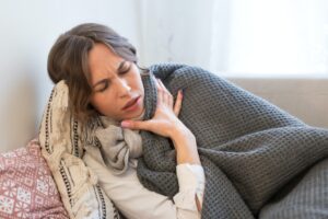 sick woman feel unwell from sore throat cough lying in bed covered with blanket need medication