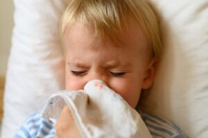 the little boy blows his nose in his handkerchief runny nose in a child the concept of colds